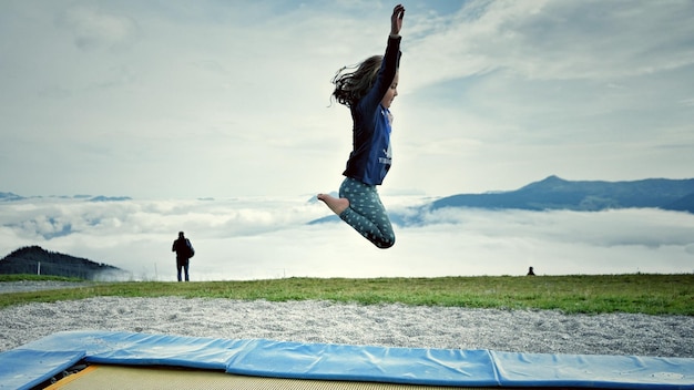 Zdjęcie dziewczyna skacząca z mężczyzną stojącym na trawie na tle przeciwko niebu