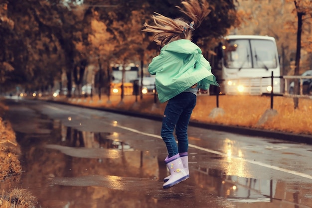 dziewczyna skacze w kałużach w jesiennym deszczu