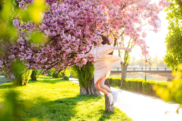 Dziewczyna skacze w różowym parku kwiatów wiśni wakacje z dziewczyną w sakura dziewczyna i sakura piękna młoda...