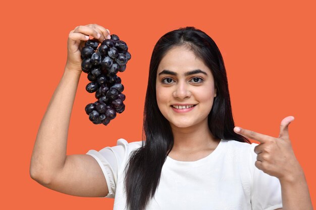 dziewczyna smakosza ubrana w białą koszulkę uśmiechnięta i trzymająca winogrona indyjska modelka pakistańska