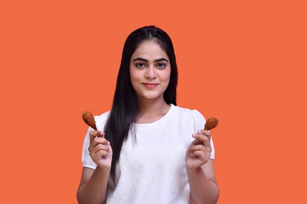 dziewczyna smakosza w koszulce uśmiechnięta i trzymająca podudzie patrząca na kamerę indyjski model pakistański