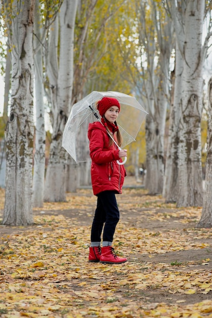 Dziewczyna spaceruje i bawi się przezroczystym parasolem w parku Jesienna atmosfera