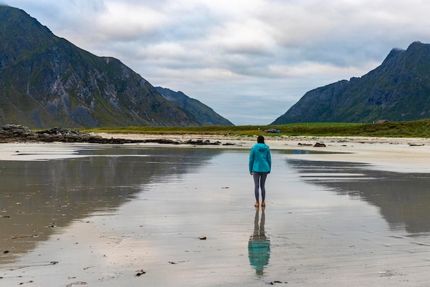 dziewczyna spaceruje po słynnej plaży surferów - plaży uttakleiv na lofotach w norwegii