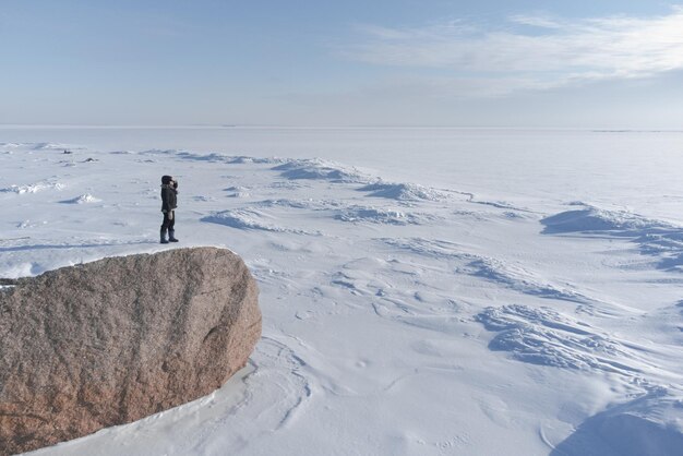Zdjęcie dziewczyna stoi na skalistym brzegu zamarzniętego morza i patrzy w odległość