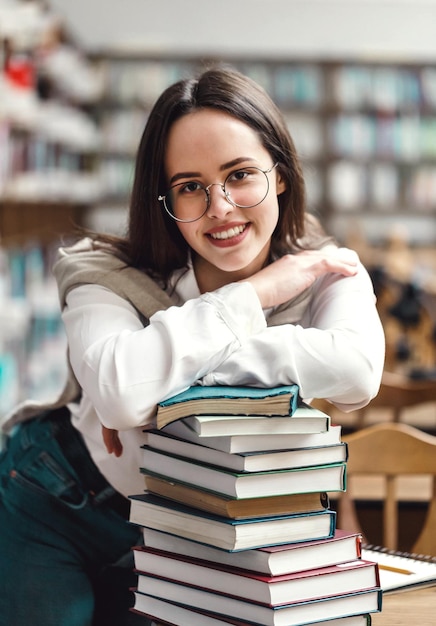 Dziewczyna stojąca z rękami złożonymi na książkach w bibliotece