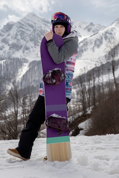 Dziewczyna stojąca ze snowboardem na tle gór