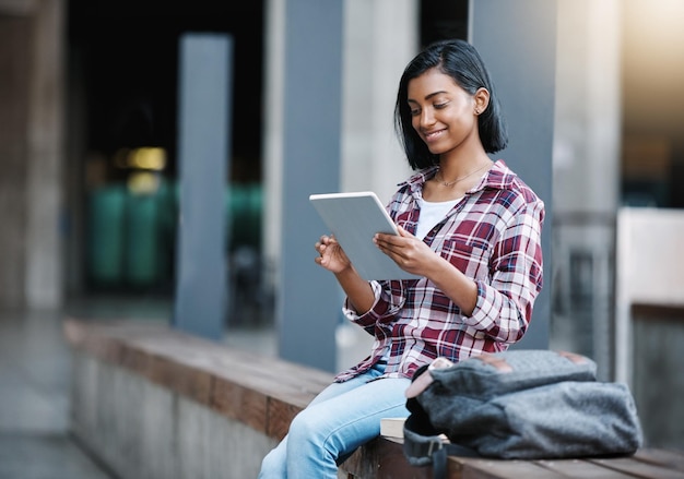 Dziewczyna studentka uniwersytetu i tablet na kampusie z torbą edukacji i czytania w szkole biznesowej Indyjska osoba powiadomienie i aplikacja e-learning dla oceny studiów lub szczęśliwy dla wyników w college'u