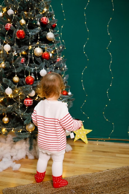 Dziewczyna szuka prezentów od Świętego Mikołaja pod choinką Dużo jasnych zabawek Wakacje w USA