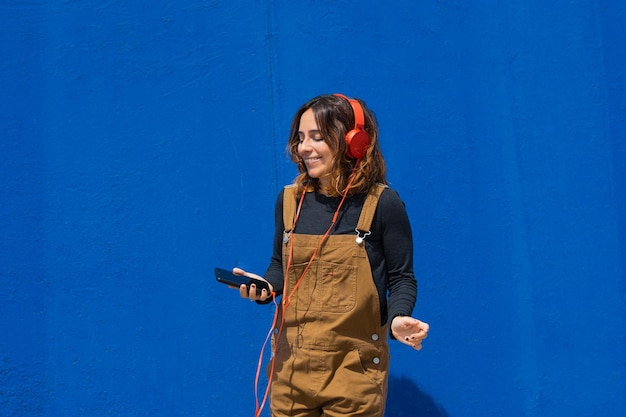 Dziewczyna tańcząca z czerwonymi słuchawkami telefon na niebieskim tle