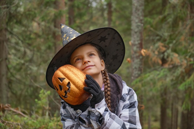 Dziewczyna trzyma błyszczącą dekoracyjną latarnię z dyni na halloween