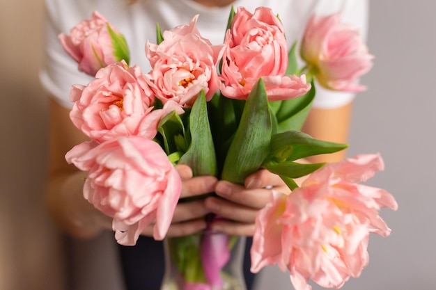 Dziewczyna trzyma różowe tulipany w szklanym wazonie Zbliżenie