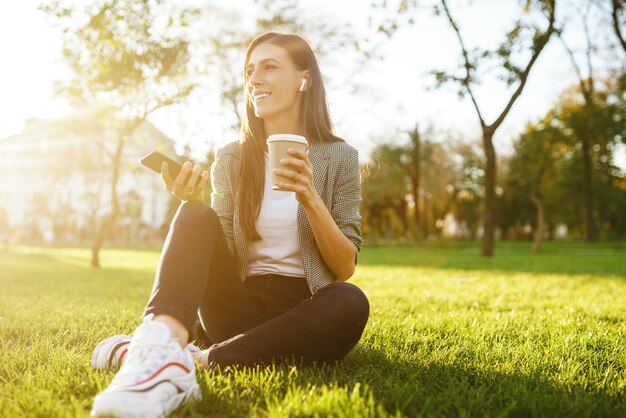 Dziewczyna trzyma telefon i kawę w dłoni Sunset Summertime