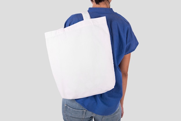 Dziewczyna trzyma torby płótno tkaniny do makiety pusty szablon na białym tle na szarym tle.