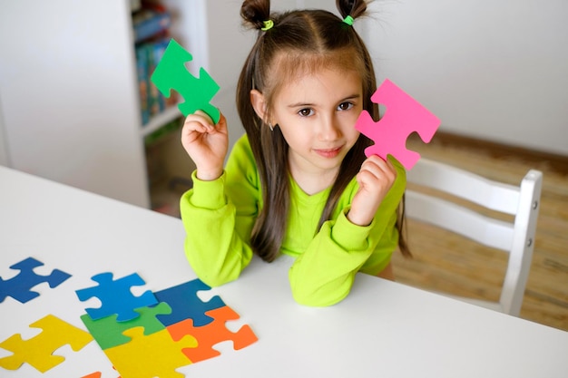 Dziewczyna trzyma w dłoniach dwa różne elementy układanki, międzynarodowy symbol autyzmu
