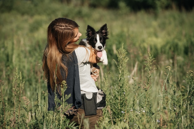 Dziewczyna trzymać na rękach czarno-biały szczeniak rasy border collie w polu