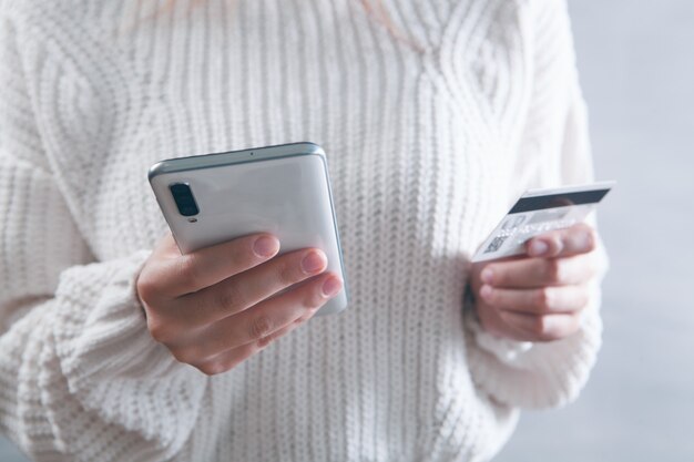 Dziewczyna trzymająca w rękach telefon i kartę bankową