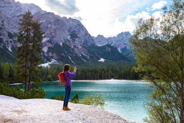 Dziewczyna turysta robi zdjęcie smartfonem nad jeziorem Braies, Dolomity, Włochy