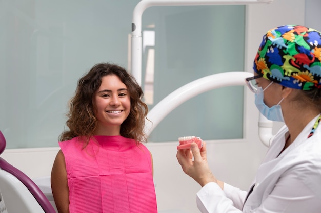 Dziewczyna uśmiecha się do stomatologii, pokazując jej szynę.