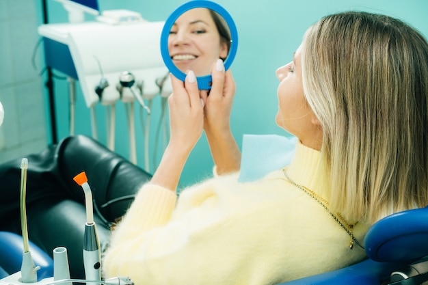 Zdjęcie dziewczyna uśmiecha się i patrzy w lustro w stomatologii