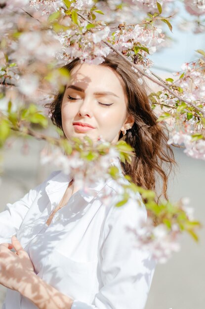 Dziewczyna w białej koszuli w pobliżu drzew sakura Sakura kwitnie