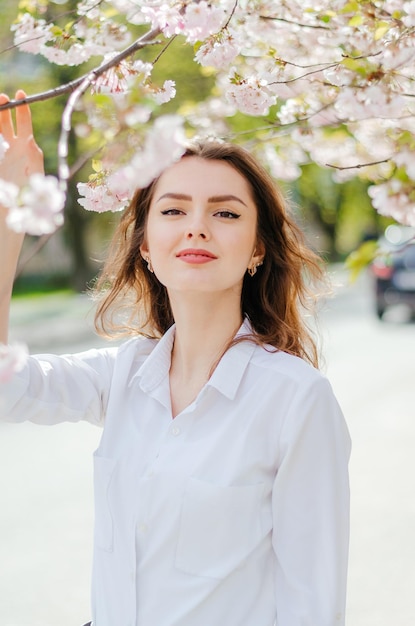 Dziewczyna w białej koszuli w pobliżu drzew sakura Sakura kwitnie