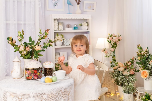 Dziewczyna w białej sukience siedzi przy stole i ogląda święta wielkanocne