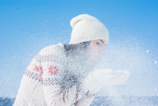 Dziewczyna w białym zimowym swetrze wieje na śniegu leci na wietrze