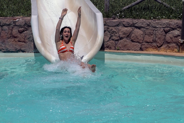 Dziewczyna w bikini bawi się podczas spadania ze zjeżdżalni w parku wodnym