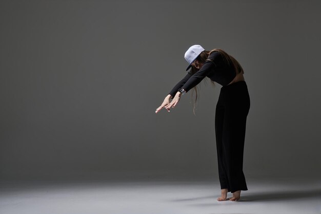 Dziewczyna w ciemnych ubraniach tańczy i skacze na ciemnym tle nowoczesnego tańca