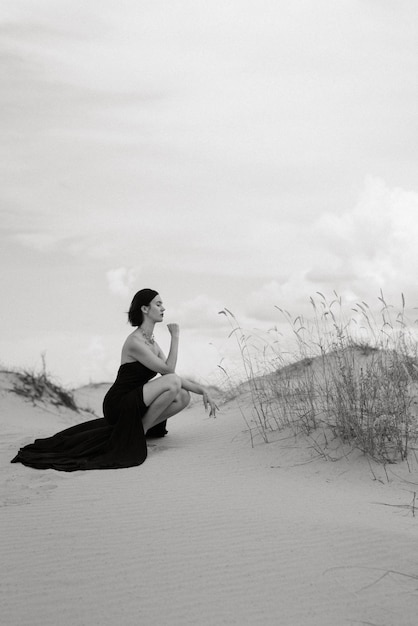 Dziewczyna w czarnej długiej sukni na piaszczystej pustyni