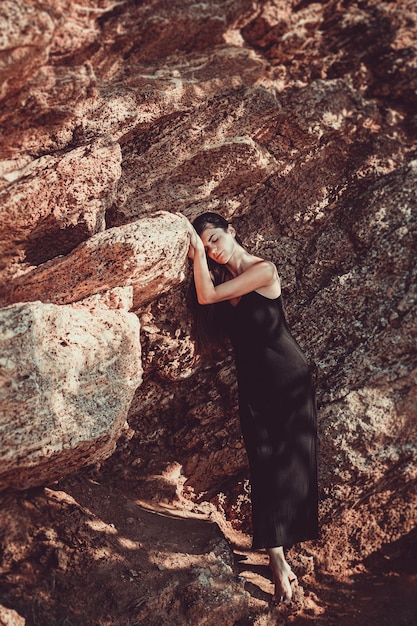 Dziewczyna w czarnej sukience pozowanie na tle piaskowych skał Portret