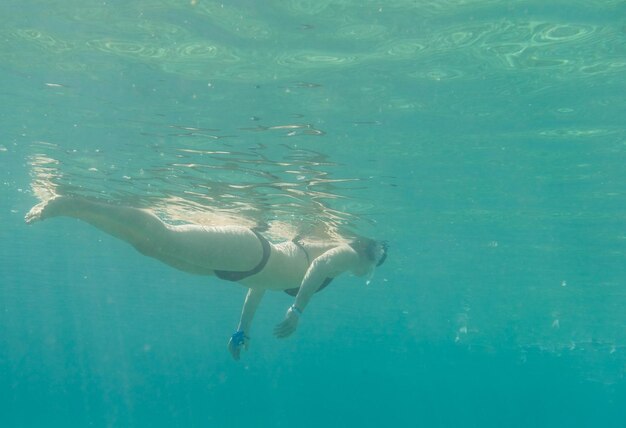 Zdjęcie dziewczyna w czarnym bikini nurkuje w czystej wodzie podczas wakacji.