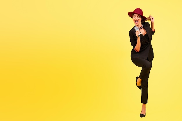 Dziewczyna w czarnym garniturze na żółtym tle śpiewa w pełnym wzroście muzyki portretowej mikrofonu retro