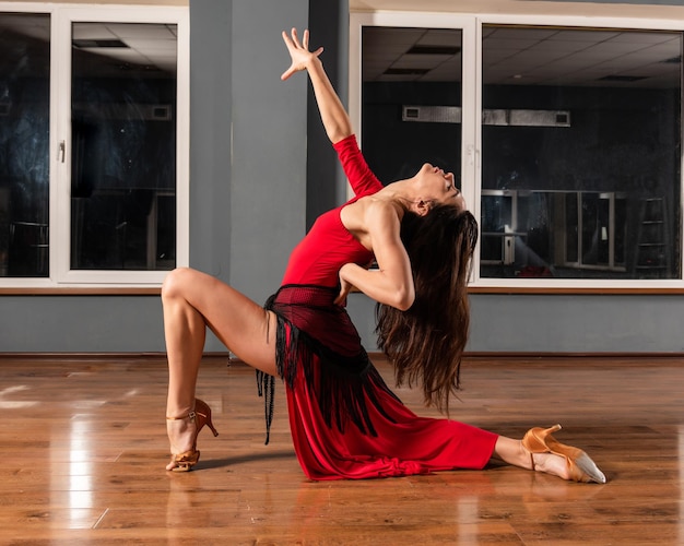 Dziewczyna w czerwonej sukience trenuje w studiu tańca