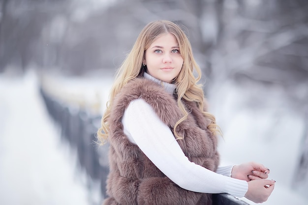dziewczyna w futrzanej kamizelce spaceruje zimą na zewnątrz / dorosły młody model w zimowym ubraniu futro