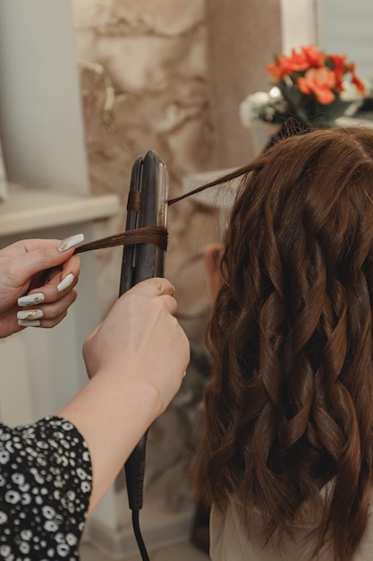 Dziewczyna w gabinecie kosmetycznym robi swoje włosy Stylizacja włosów dla kobiet na płaskiej żelazku blog estetyka uroda styliści włosów lokówka lokówka miejsce na tekst