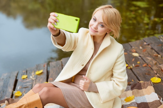 Dziewczyna w jesiennym parku sprawia, że koncepcja jesiennej sprzedaży selfie