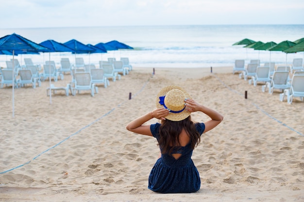 dziewczyna w kapeluszu siedzi na plaży.