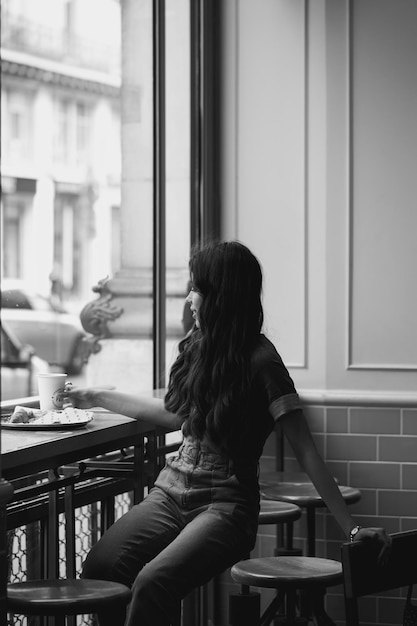 Dziewczyna w kawiarni przy filiżance kawy w pobliżu okna. Model w kawiarni z kawą. Dziewczyna