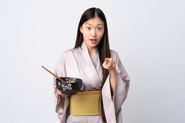 Dziewczyna w kimono trzyma miskę makaronu