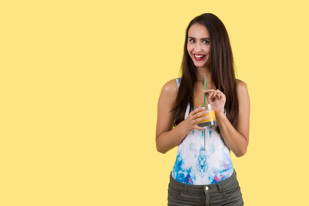 Dziewczyna w kolorowym podkoszulku bez rękawów pije sok
