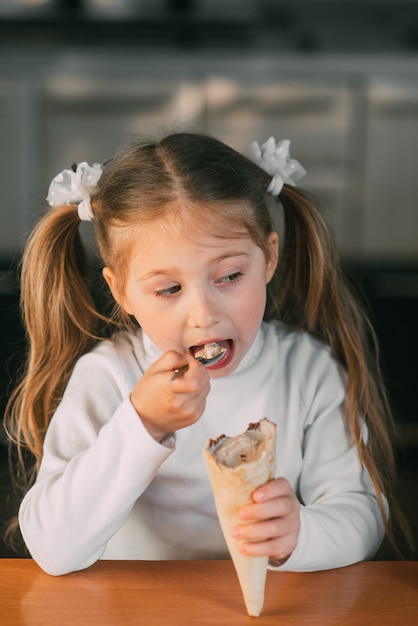 Dziewczyna w kuchni jedząca lody z łyżką przy świetle dnia bardzo słodkim