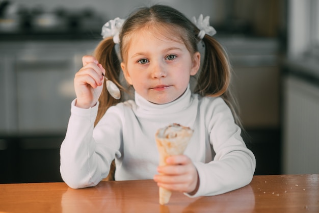 Dziewczyna w kuchni jedząca lody z łyżką przy świetle dnia bardzo słodkim