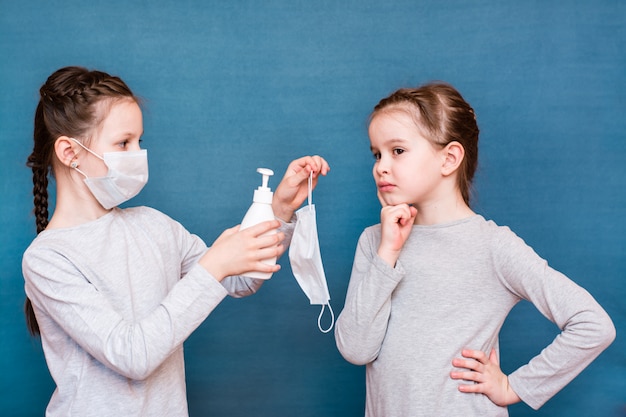 Dziewczyna w masce medycznej oferuje innej dziewczynie czystą maskę i środek dezynfekujący. Ochrona dziecka
