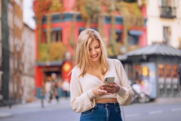 Zdjęcie dziewczyna w mieście uśmiecha się do telefonu