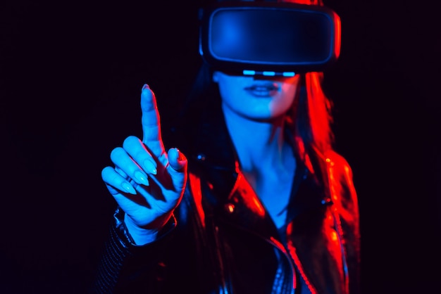 Dziewczyna w okularach wirtualnej rzeczywistości dotyka palcem ekranu projekcyjnego