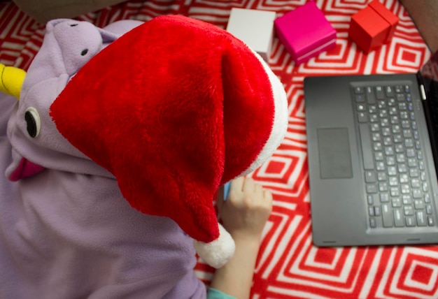 Zdjęcie dziewczyna w piżamie i santa hat zakupy online za pomocą karty kredytowej.