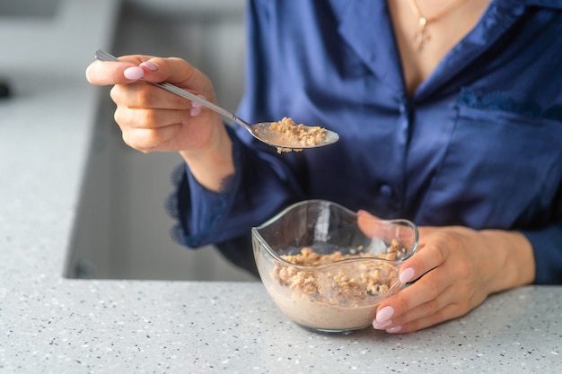 Dziewczyna w piżamie zjada muesli na śniadanie