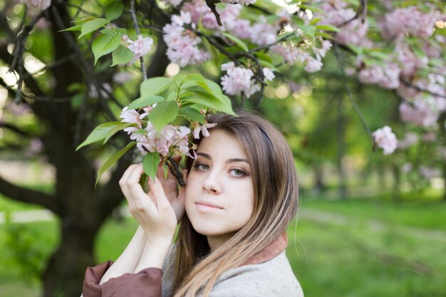 dziewczyna w pobliżu kwitnącej sakury. Wiosna jest teraz. Kwiaty wiśni. Sakura o zmierzchu. portret o zachodzie słońca