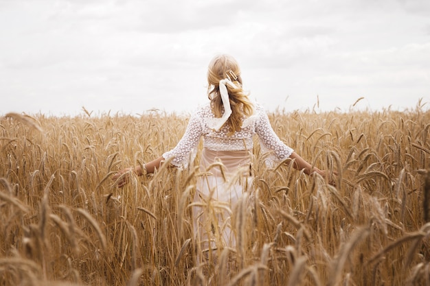 Dziewczyna w polu pszenicy w lecie. widok z tyłu